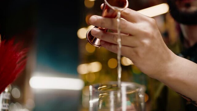 professional bartender creates a cocktail drink pours alcohol into a measuring glass at the bar close-up