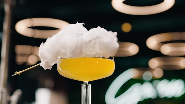 fresh tasty alcoholic cocktail with cotton candy rotates on the bar counter in a bar or restaurant