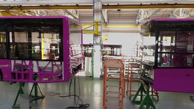 Fuchsia colored bodies of buses and trolleybuses on the conveyor line of the passenger transport plant.