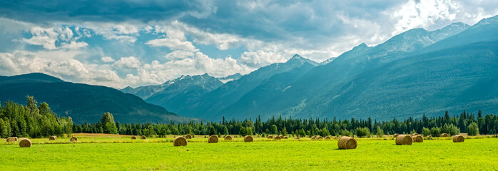 Panorama of mountains behind haystacks in a farm field in British Columbia, Canada