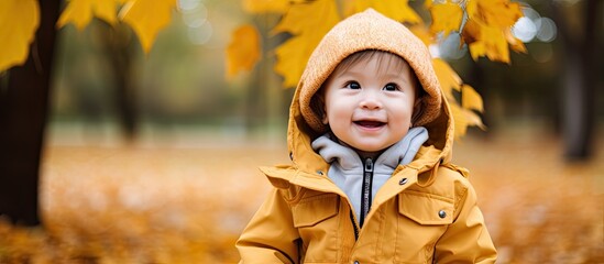 Stylish Asian toddler walks happily in autumn park wearing trendy jacket and hat