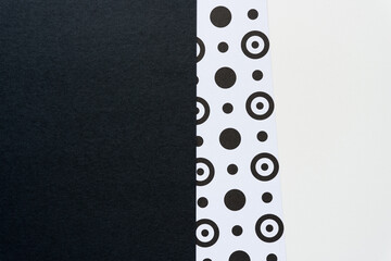 white paper with black dots and rings tucked slightly beneath black and white paper solids