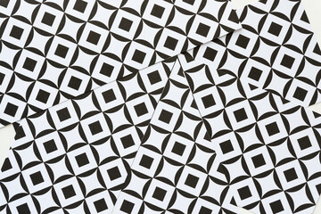 overlapping paper with black and white paper featuring square-in-box repeating pattern