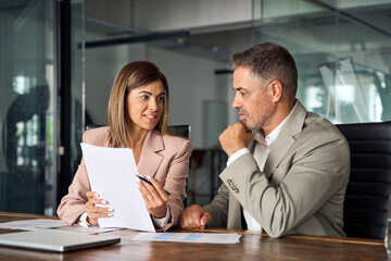 Female lawyer attorney or bank manager consulting male client holding papers during legal advice. Two business executives discussing financial accounting documents report working at meeting in office. - obrazy, fototapety, plakaty