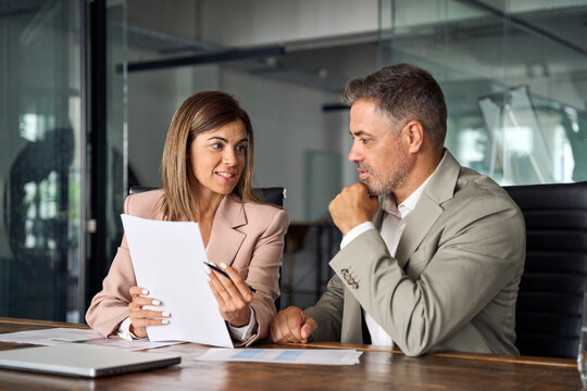 Female lawyer attorney or bank manager consulting male client holding papers during legal advice. Two business executives discussing financial accounting documents report working at meeting in office.
