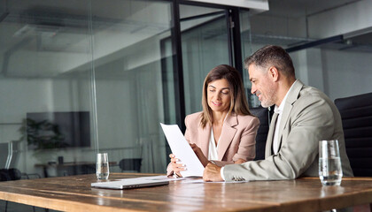 Two professional executives discussing financial accounting papers working with paperwork in...