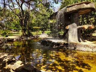 Fonte d'água de pedra, bem trabalhada e funcionando, no meio de lago artificial, em Jardim Japonês localizado em Caldas Novas, Goiás - 138