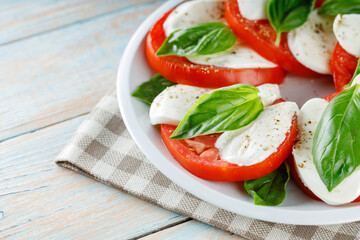 Delicious Caprese Salad with ripe tomatoes and mozzarella cheese with fresh basil leaves. Italian food. Close up