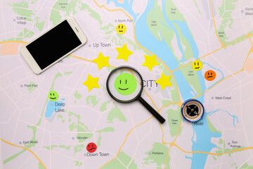 Fototapeta na wymiar Magnifier with rating smiles, stars, compass and mobile phone on city map