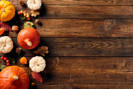 Autumn background with colorful pumpkins, berries, fall leaves, walnuts on wooden table. Thanksgiving, Halloween, Autumn, Harvest concept. Flat lay, top view, copy space.