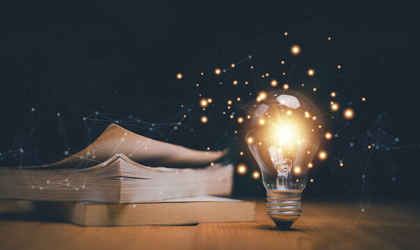 Glowing light bulb near a stack of books, Educational knowledge and business education ideas, Innovations, Inspiring from read concept, knowledge and searching for new ideas. Thinking for new idea.