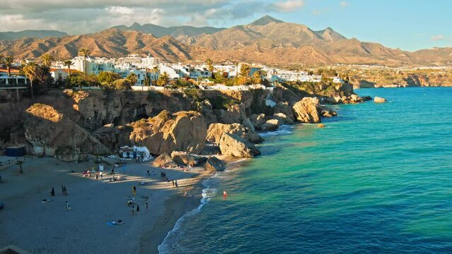 Panoramic view of Playa de la Calahonda from Balcon de Europa in Nerja, Spain. Tourists have a good time in Spain relaxing at the beach with mountains in the background.