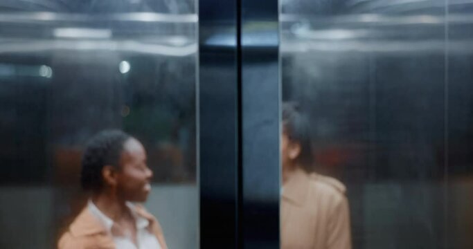 Elevator door, business women and conversation in a office building at company going down. Female staff, happy and speaking of professional worker with a smile at hotel with workforce and job travel