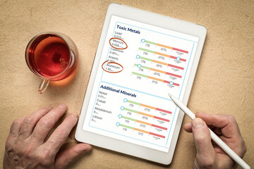 reviewing medical test results on a digital tablet - toxic metals and other minerals with high levels of mercury and aluminum from a hair sample