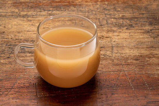 glass cup of beef bone broth on a grunge wood table