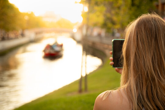 40 Years Old Blonde Tourist Woman With Mobile Phone Front Sea Canal With Moliceiro Boat At Golden Sunset Aveiro, Portugal 