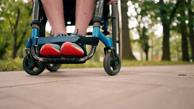 Close-up of legs of man in wheelchair in city park mobility health concept active lifestyle