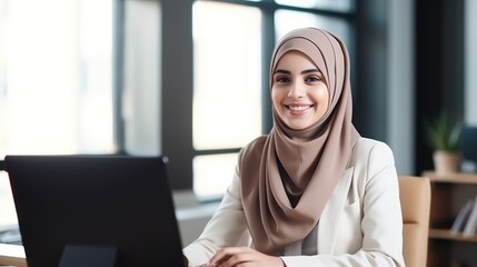 Attractive middle eastern businesswoman woman posing at her work place sitting at her desk using a...