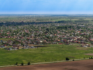 Fototapeta na wymiar Aerial city view behind the green field