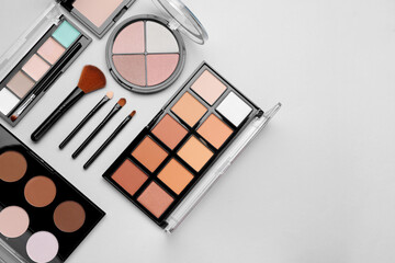Colorful contouring palettes and brushes on light grey background, flat lay with space for text....