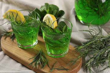 Obraz na płótnie Canvas Glasses of refreshing tarragon drink with lemon slices on tablecloth