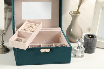 Jewelry box with many different accessories, perfume and decor on white table