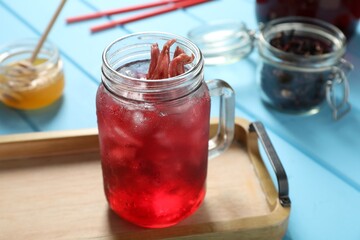 Mason jar of delicious iced hibiscus tea on light blue wooden table