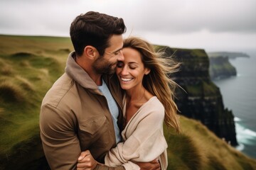 Couple in their 30s smiling at the Cliffs of Moher in County Clare Ireland