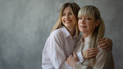 Mom and adult daughter, family portrait, two generations of women. Portrait in the studio in bright...