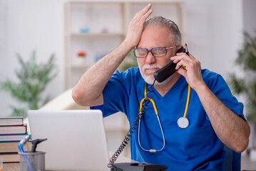 Old male doctor in telemedicine concept