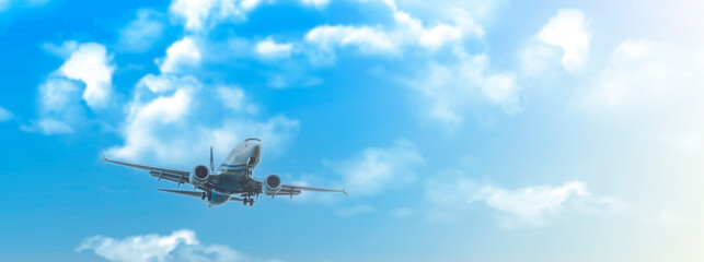 Passenger jet landing against a blue sky with white clouds on soft sunlight