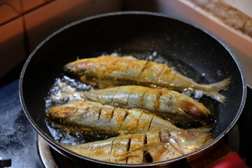 fried mackerel with turmeric spices in a black pan. seafood. ikan kembung goreng.