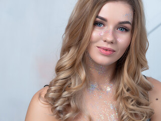 Sequins in makeup, a fashionable youth trend. Beautiful young girl happy and laughing, portrait in...