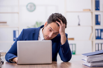 Young male employee and too much work in the office