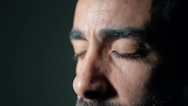 Young Arabian man opening eyes in dark room.