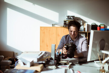 Young photographer going through his camera at his desk office