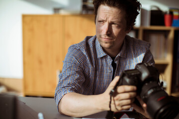 Young photographer going through his camera at his desk office