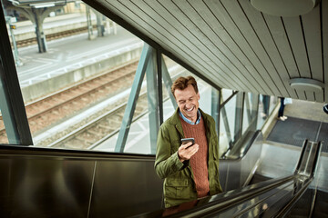 Middle aged man using a smart phone while waiting for a train at the station