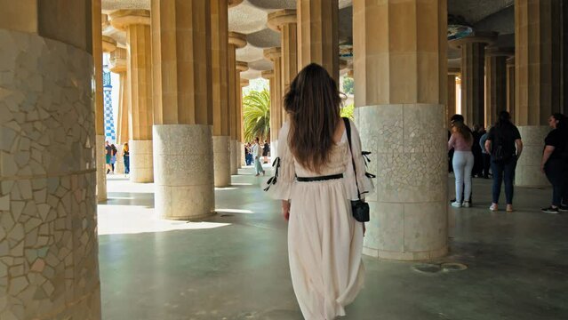 Tourists visiting Park G&uuml;ell by Antoni Gaudi in Barcelona Spain Europe. People exploring and looking at art Mosaic covered buildings and sculptures in a verdant park