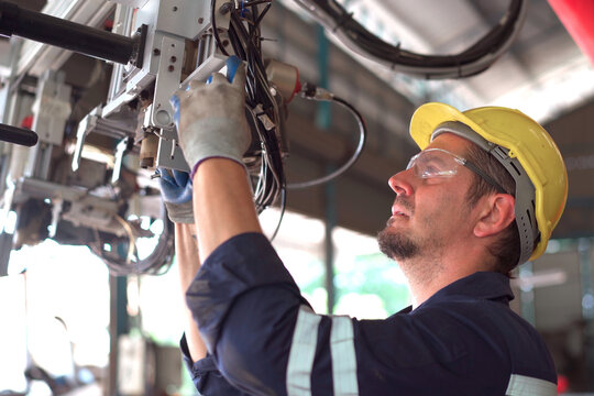 Senior professional electrical or industrial engineer inspecting and repairing a robotic system in the manufacturing factory close up. Robotic technician repairing - fixing a automated machine.