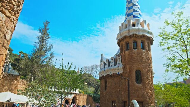 Tourists visiting Park G&uuml;ell by Antoni Gaudi in Barcelona Spain Europe. People exploring and looking at art Mosaic covered buildings and sculptures in a verdant park