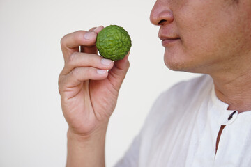 Closeup man holds  kaffir lime fruit to smell. Concept, herbal fruit, aromatherapy, Kaffir lime essential oil has properties to help relieve stress,anxiety and dizzy.  