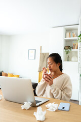 Chinese woman feel sick working from home. Asian female blowing nose with tissue holding cup of herbal tea. Vertical - obrazy, fototapety, plakaty