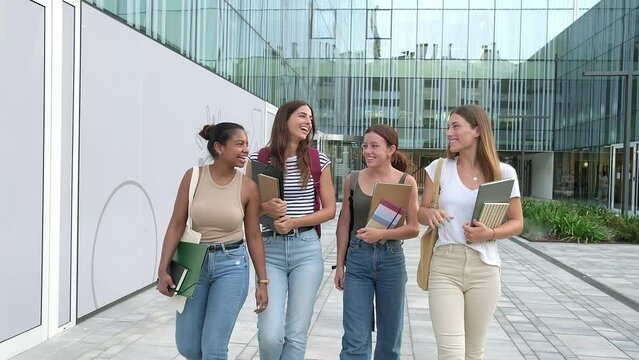 Traveling video shot of multiracial happy female university students walking to class while talking in college campus.HD
