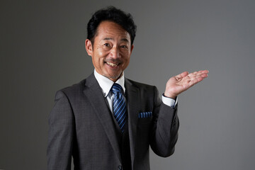 右側を手の平で指す中年のビジネスマン　黒背景