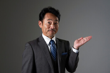 右側を手の平で指す中年のビジネスマン　黒背景