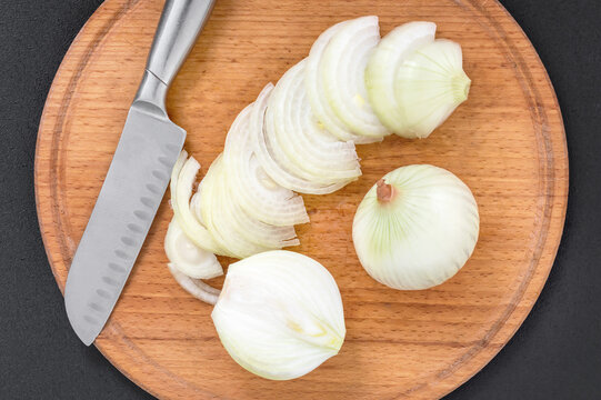 Cutted onion with knife on cutting board. Top view.