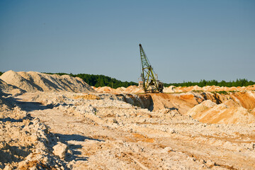 Walking excavator operates in chalk quarry with piles line