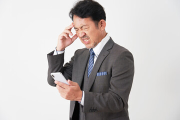 スマホを持って困る中年のビジネスマン　白背景