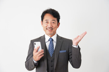 スマホを持って手の平で右側を指す中年のビジネスマン　白背景